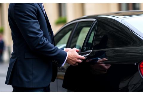 Chauffeur élégant de Veloce Voyage ouvrant respectueusement la portière d'une voiture de luxe pour un client.